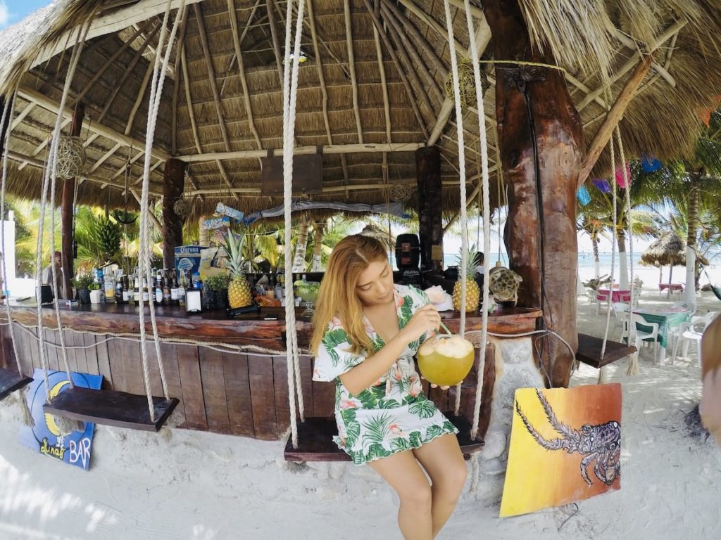 Palapa bar in the sea of Costa Maya, young woman drinking coconut water